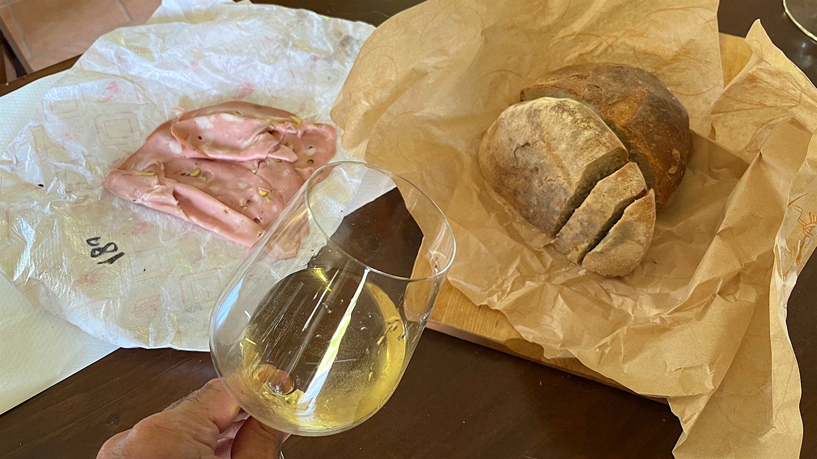 A plate of mortadella with a glass of Asprinio